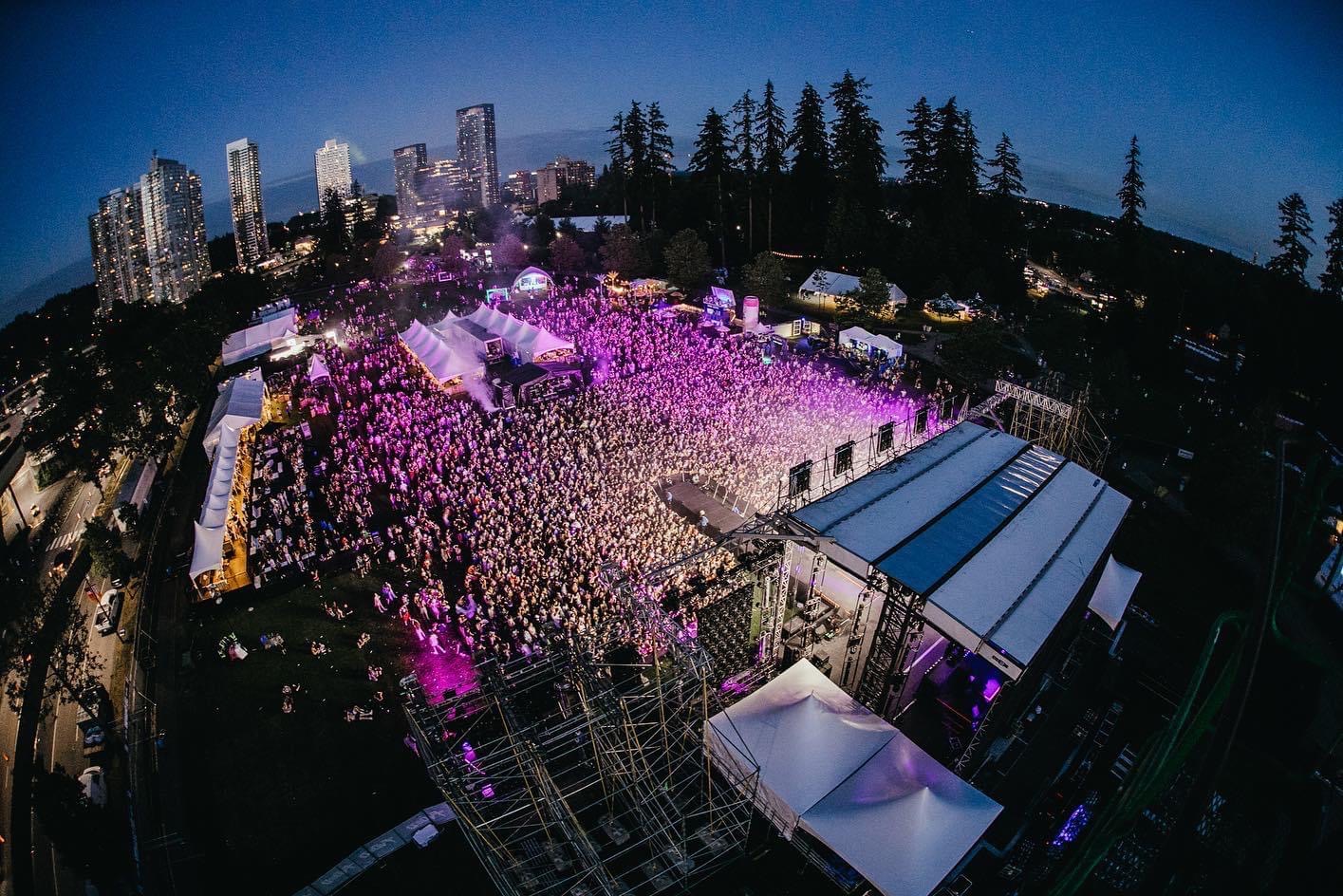 White tents flanking a stage at a Vancouver music festival at twilight
