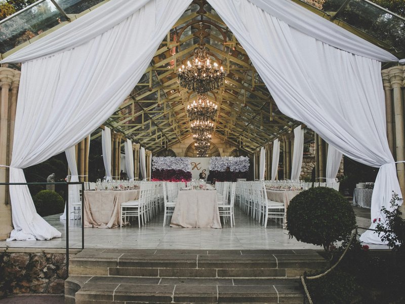 White draped fabric and chandeliers inside a wedding tent reception